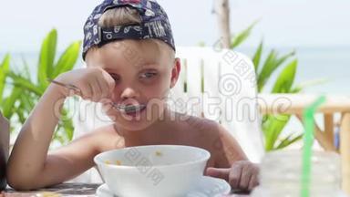 小男孩在户外吃<strong>粥</strong>。 在海滩上吃<strong>粥</strong>的男孩